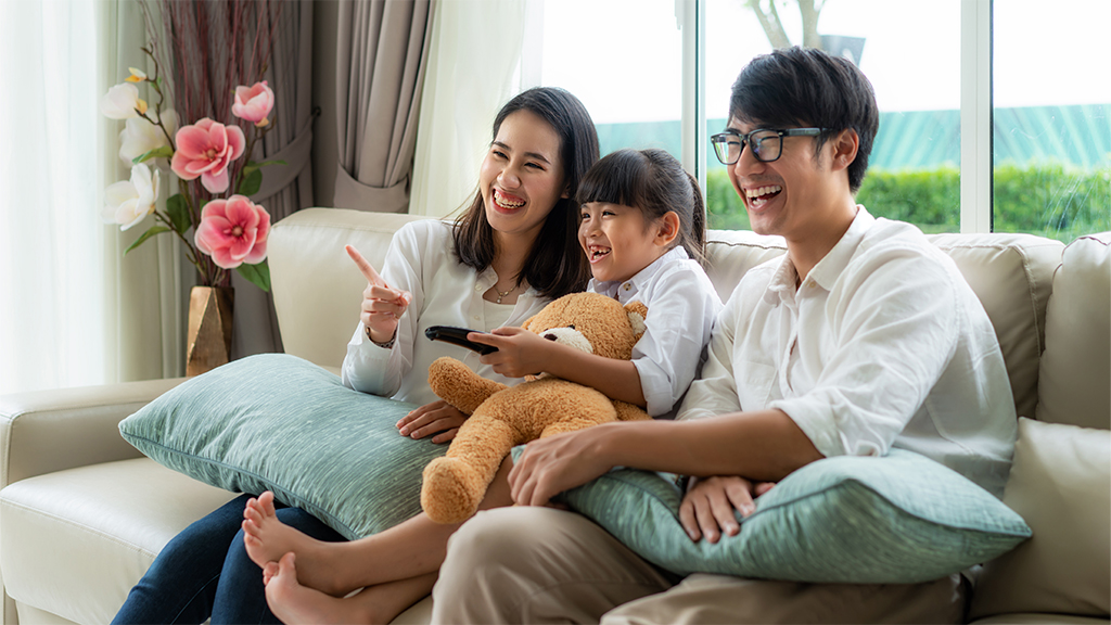 Une famille américaine d'origine asiatique regarde la télévision sur un canapé