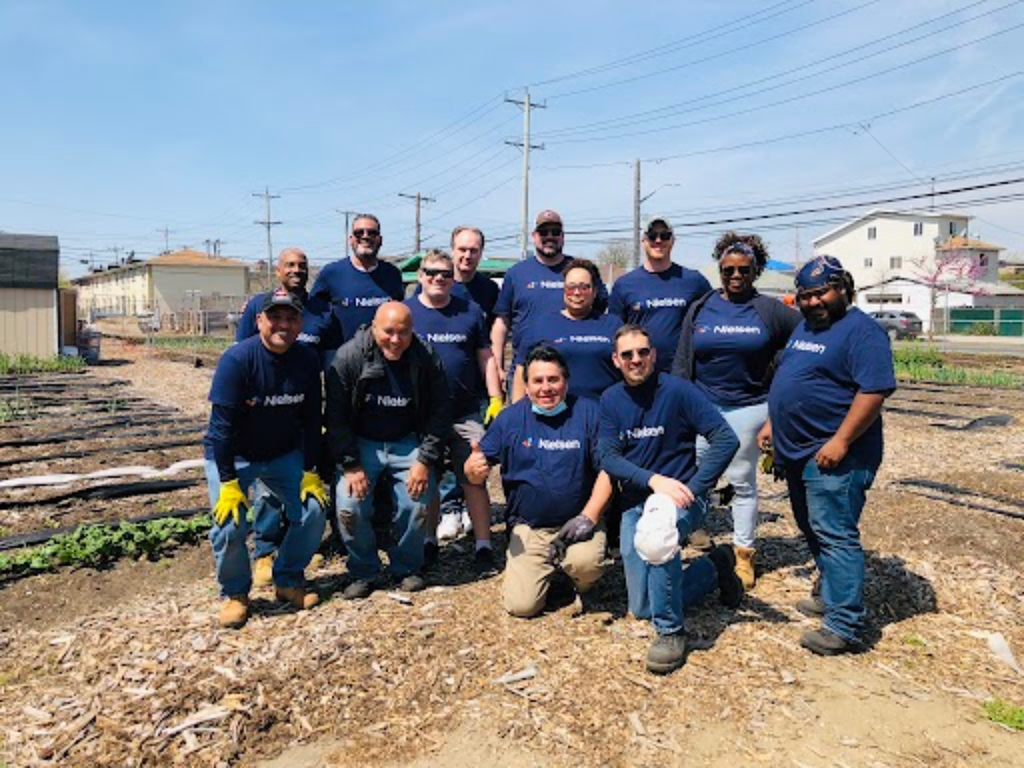 Un grupo de voluntarios posa en un campo con camisetas de Nielsen