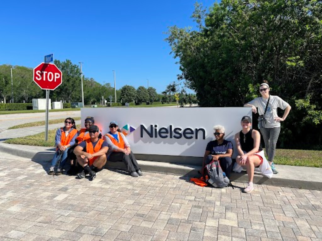Group of volunteers pose in front of Nielsen office sign