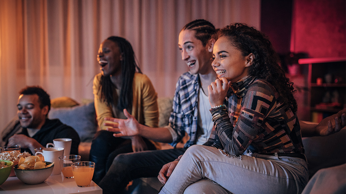 Tre donne che guardano la TV e bevono bevande fredde