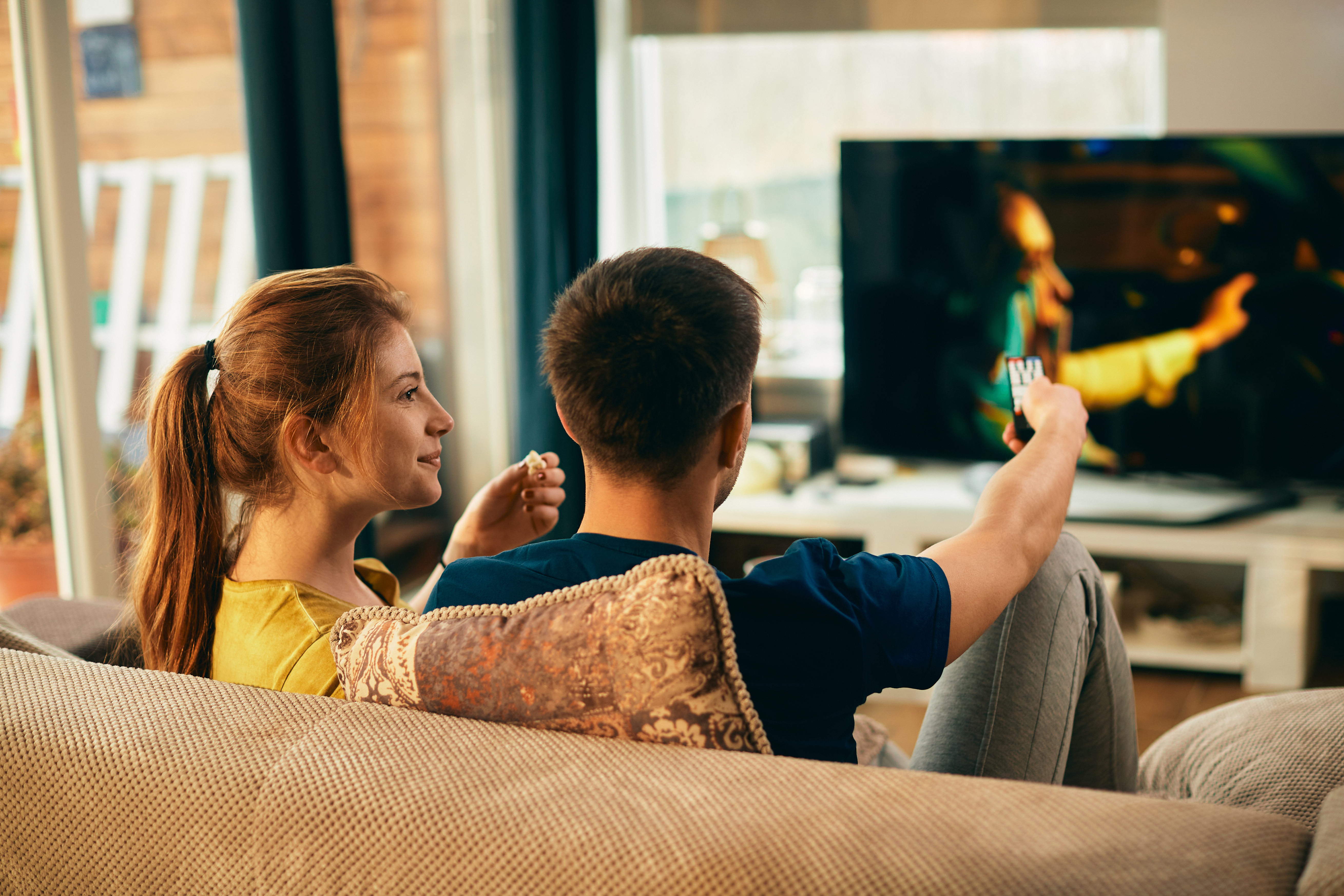 Una coppia che si rilassa sul divano e guarda la TV