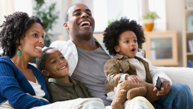Una familia negra sentada junta y disfrutando de los programas de televisión