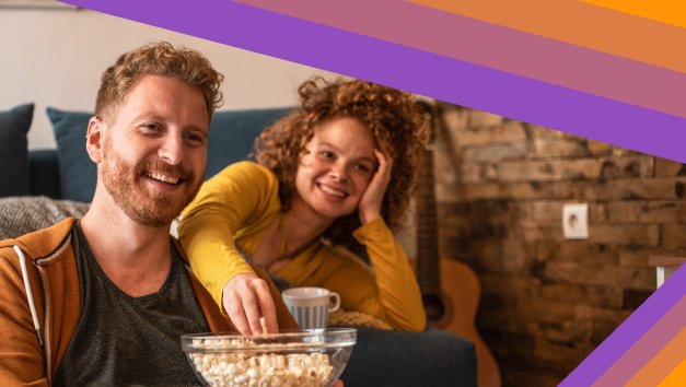 A woman having Pop corn on hand and  enjoying TV show with coffee