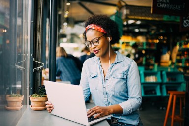 Fokussierte junge afrikanische Frau, die in einem Café online arbeitet