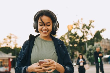 Une femme écoutant de la musique avec des écouteurs et marchant dans la rue